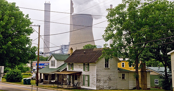 A coal-fired power plant billows clouds of pollution over nearby homes.